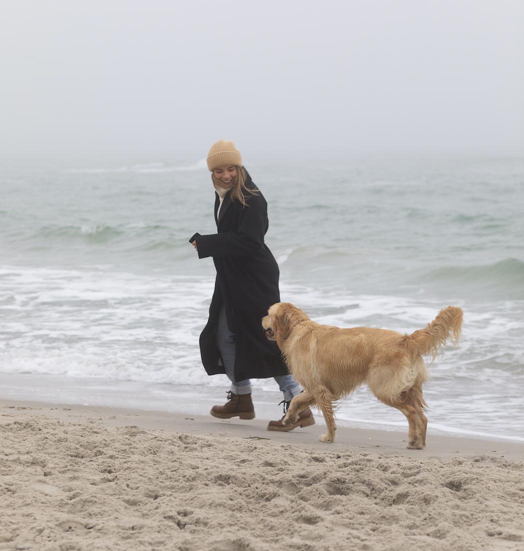Vrouw met hond op het strand bij mistig weer